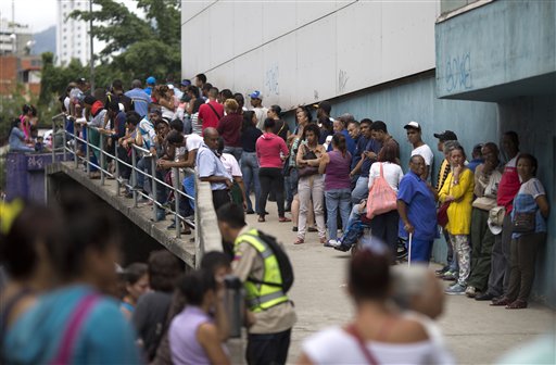 En esta imagen, tomada el 18 de noviembre de 2016, un grupo de personas espera en el exterior de un supermercado para comprar comida subvencionada por el gobierno en Caracas, Venezuela. A medida que la producción nacional se frena, el estado adquiere el rol de importar casi toda la comida que llega al país. (AP Foto/Ariana Cubillos)