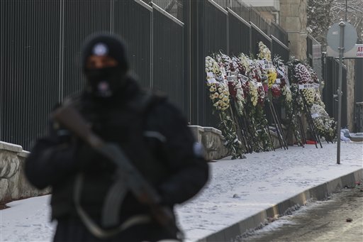 Varias coronas de flores han sido dejadas en la calle que lleva a la embajada rusa en Ankara, Turquía, el miércoles 21 de diciembre de 2016, ante la vigilancia de un policía turco, luego del asesinato del embajador ruso en Turquía, Andrei Karlov, durante la inauguración de una exhibición fotográfica. (AP Foto/Emrah Gurel)