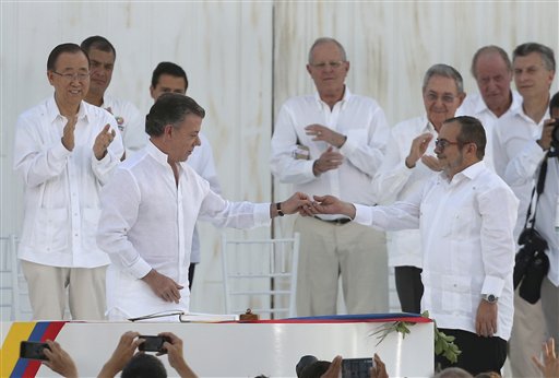 En esta imagen del 26 de septiembre de 2016, el presidente de Colombia, Juan Manuel Santos, al frente a la izquierda, le entrega un prendedor de la paz al comandante de las Fuerzas Armadas Revolucionarias de Colombia, FARC, Rodrigo Londoño, alias Timochenko, luego de firmar un acuerdo de paz entre el gobierno y las FARC en Cartagena, Colombia. Con menor fervor y una mayor dosis de incertidumbre, el gobierno colombiano firmará el jueves 24 de noviembre, por segunda ocasión en menos de dos meses, un acuerdo de paz con el principal grupo rebelde del país. (AP Foto/Fernando Vergara, archivo)