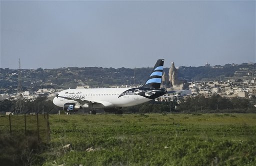Un avión de Afriqiyah Airways detenido en la pista del Aeropuerto Internacional Luqa de Malta, el viernes 23 de diciembre de 2016. Dos hombres armados secuestraron el avión con 118 personas a bordo y lo llevaron a Malta, donde amenazaron con usar granadas para hacerlo estallar. (AP Foto/Jonathan Borg)