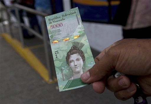 Un cliente muestra un billete nuevo de 5000 bolívares afuera de un banco en Caracas, el lunes 16 de enero de 2017.  (AP Foto/Fernando Llano)
