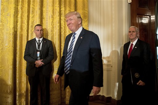 El presidente de Estados Unidos, Donald Trump (centro), acompañado por el vicepresidente, Mike Pence (derecha), a su llegada a la toma de posesión del personal de la Casa Blanca, en la East Room de la Casa Blanca, el 22 de enero de 2017, en Washington. (AP Foto/Andrew Harnik)