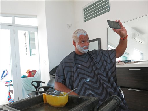 Christian Rodríguez, ingeniero civil, se toma una foto con su teléfono, luego de teñirse el cabello y la barba en San Juan, como una muestra de apoyo a la selección de beisbol de Puerto Rico, el martes 21 de marzo de 2017 (AP Foto Danica Coto)